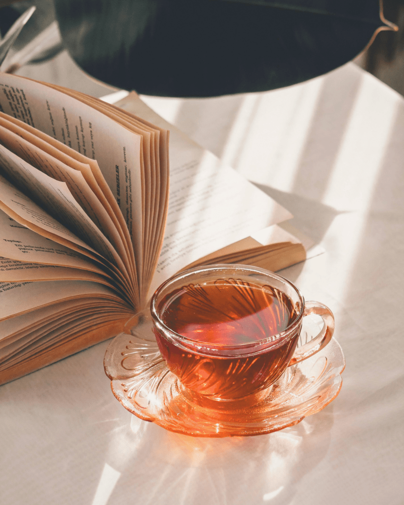 A cup of tea resting beside an open book in warm sunlight, symbolising calm awareness and reflection.