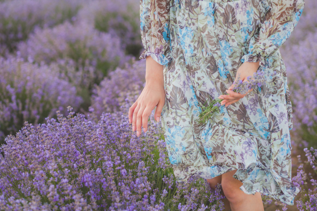 A serene photograph of a person in a floral dress walking through a lavender field, softly touching the blossoms. The image evokes peace, empowerment, and the return to self after healing from domestic abuse.