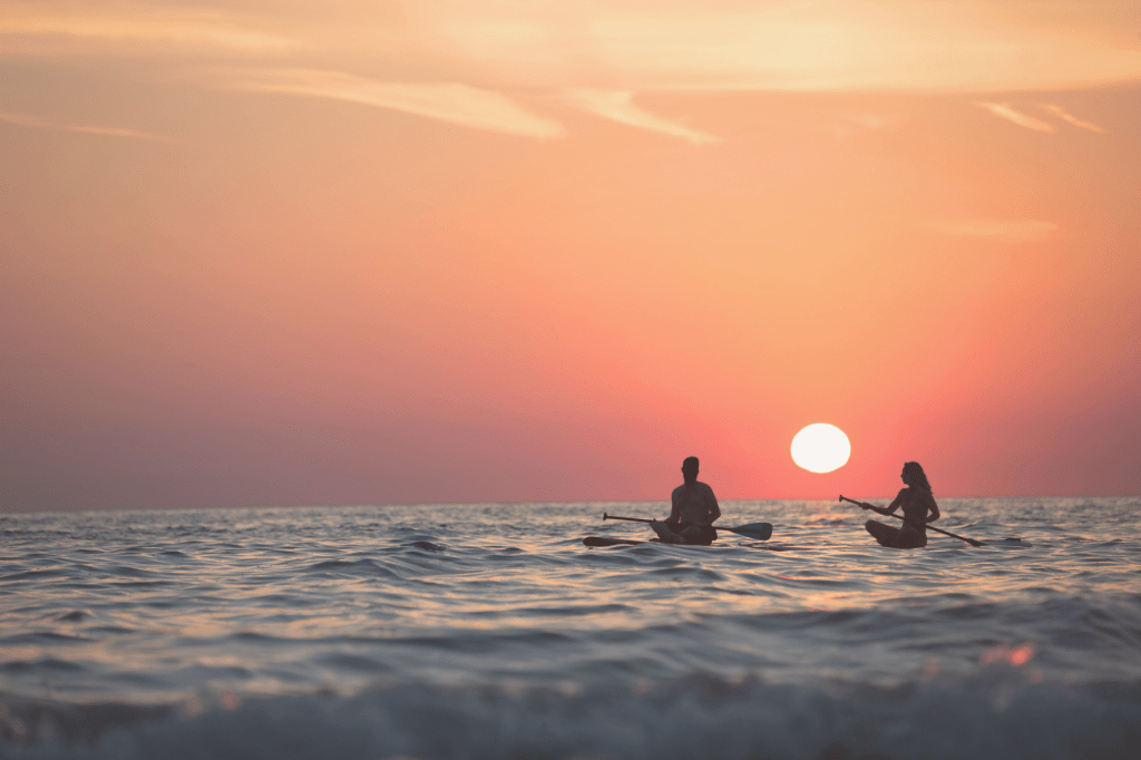 Two people kayaking on calm water at sunset, symbolising flow, connection, and the balanced confidence that comes from inner resilience.