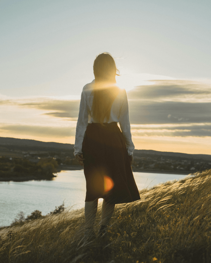 Person standing on a hill at sunset, embodying calm presence, emotional resilience, and connection with nature.