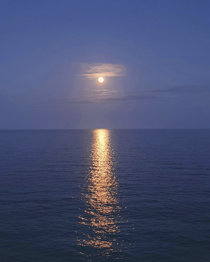 Full moon reflecting on calm ocean water, symbolising feminine cycles, reflection, and emotional flow in embodied healing.