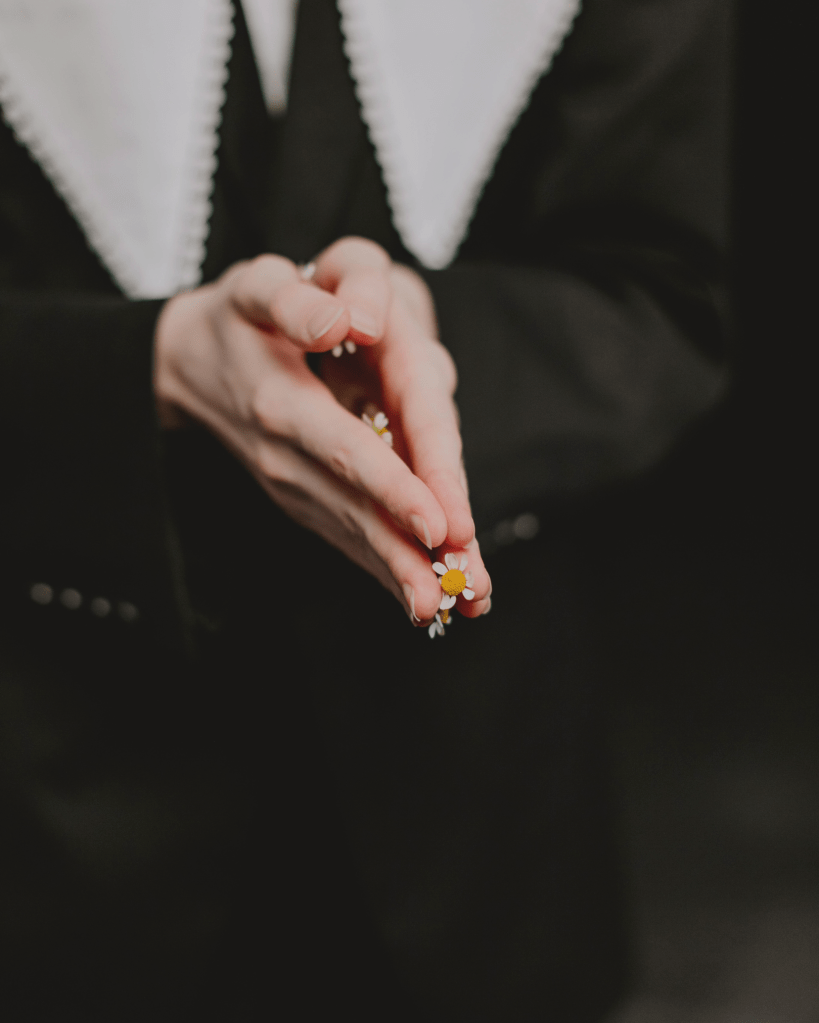 Close-up of hands gently holding small flowers, symbolising inner healing, integration of parts, and reclaiming wholeness after trauma.