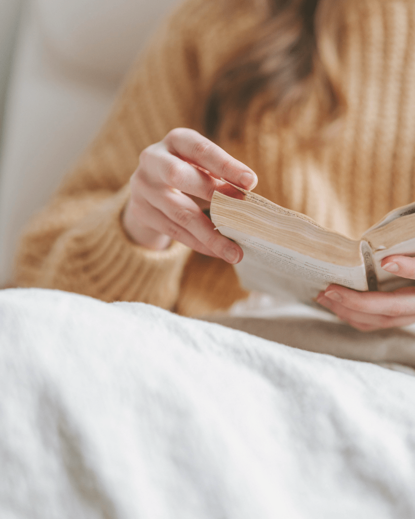 Hands holding an open book in a calm indoor setting, supporting nervous system education and regulation.
