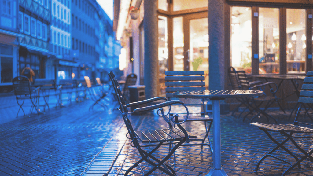 Empty outdoor café seating on a quiet street in the early morning light.