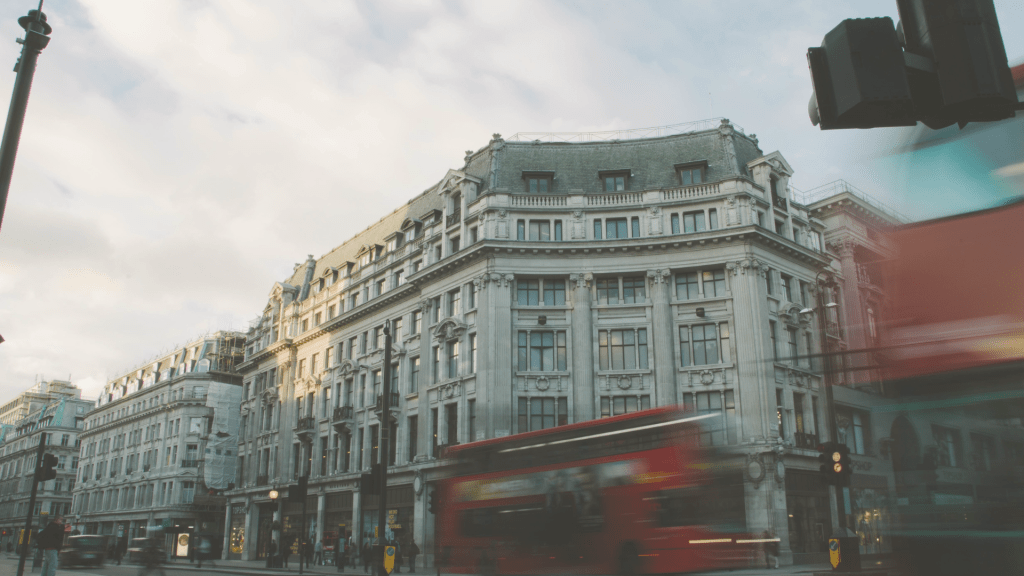 Blurred traffic passing in front of historic buildings in a city street, showing movement and pace in an everyday urban setting