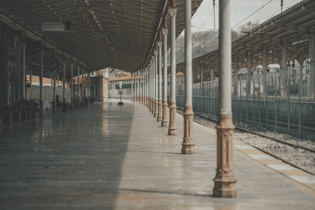 Train station platform with columns and tracks, reflecting stillness in a built environment