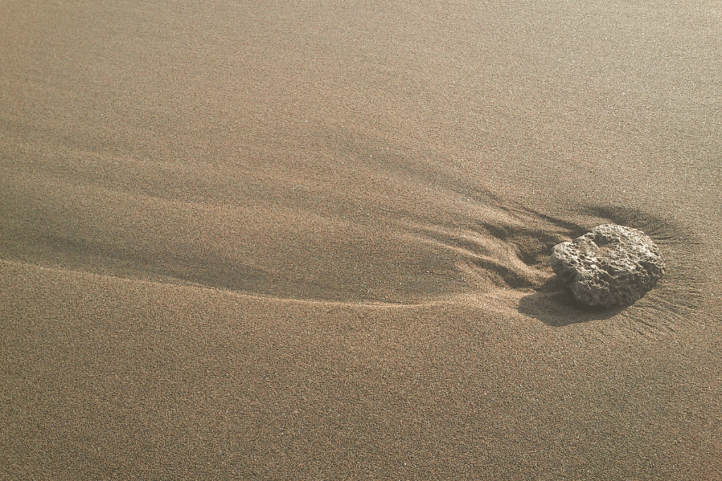 Single rock resting on smooth sand surface, showing simplicity and minimal sensory stimulation