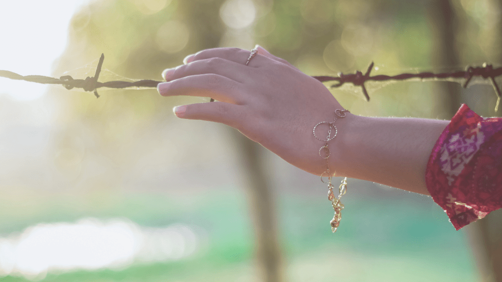Hand touching barbed wire in soft light, illustrating trauma bonds and the pull toward harmful attachment patterns after emotional abuse
