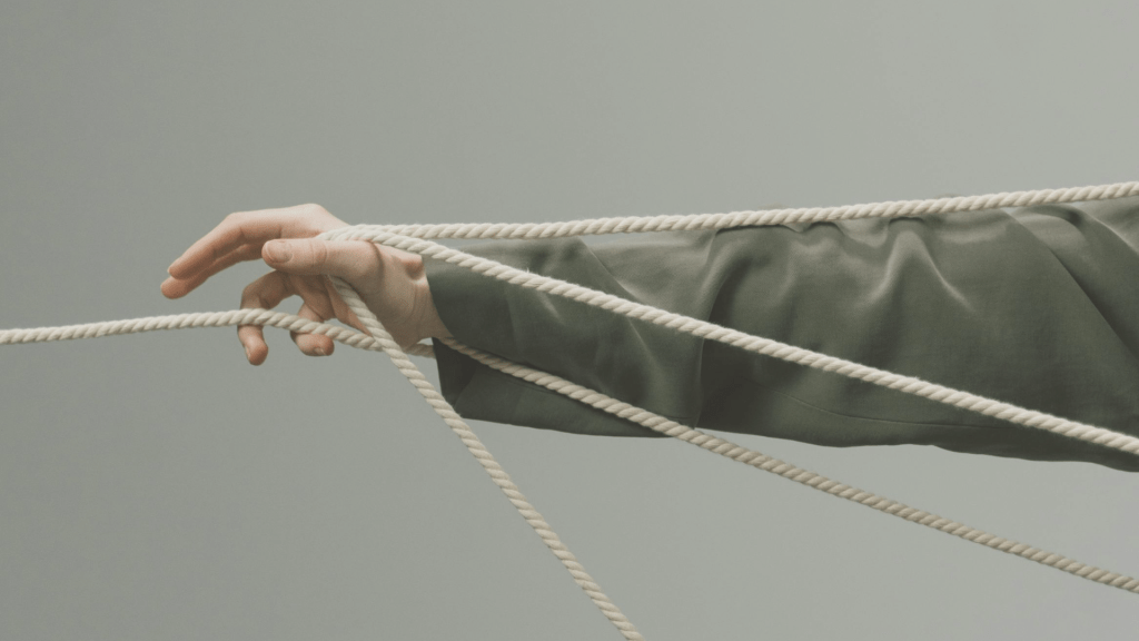 Hand entangled in rope illustrating trauma bonding and difficulty letting go of unhealthy attachment patterns after emotional abuse