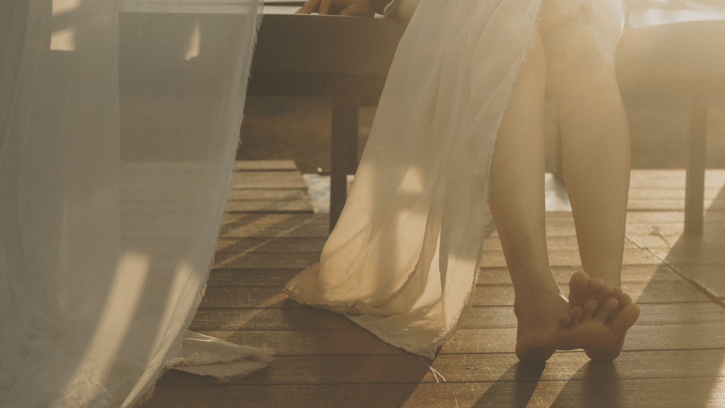 Bare feet resting on a wooden floor in warm morning sunlight, symbolising emotional safety, nervous system regulation, trauma recovery and healing after chronic stress.