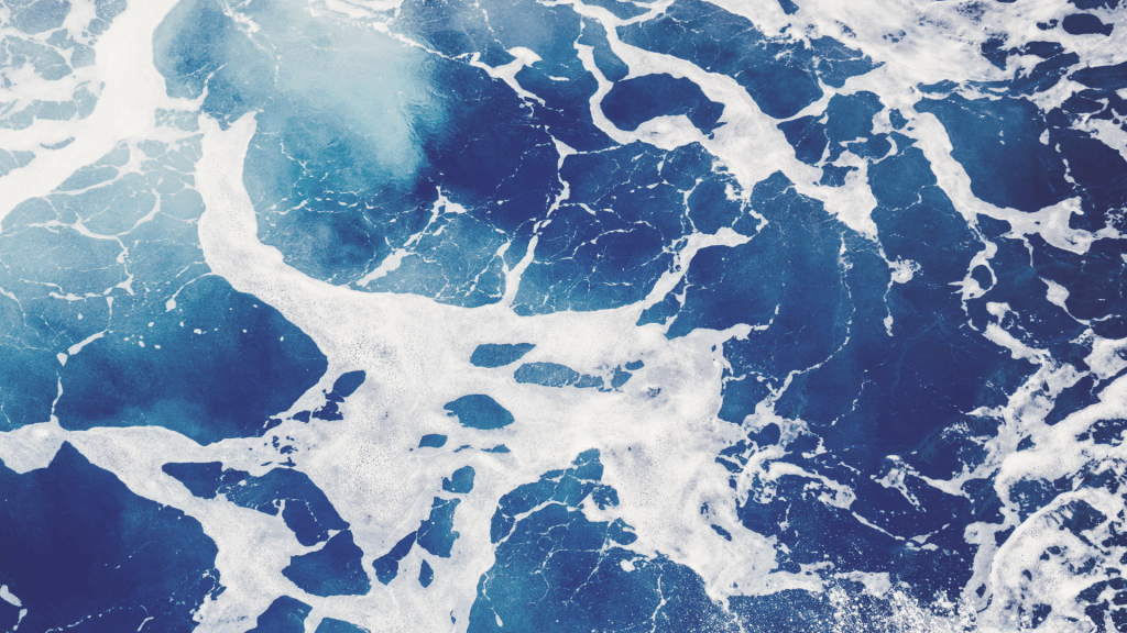 Aerial view of ocean waves forming irregular patterns, representing nonlinear change and variation over time.